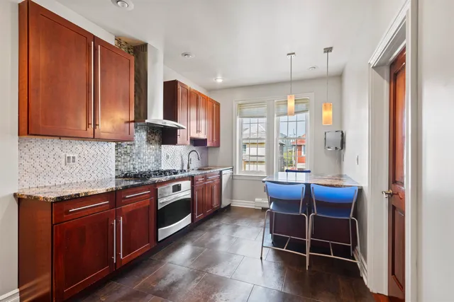a kitchen with stainless steel appliances granite countertop a stove refrigerator and cabinets