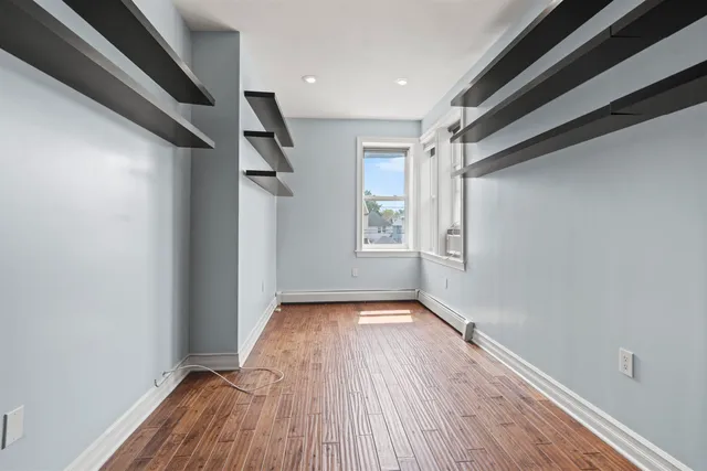 a view of empty room with wooden floor and fan