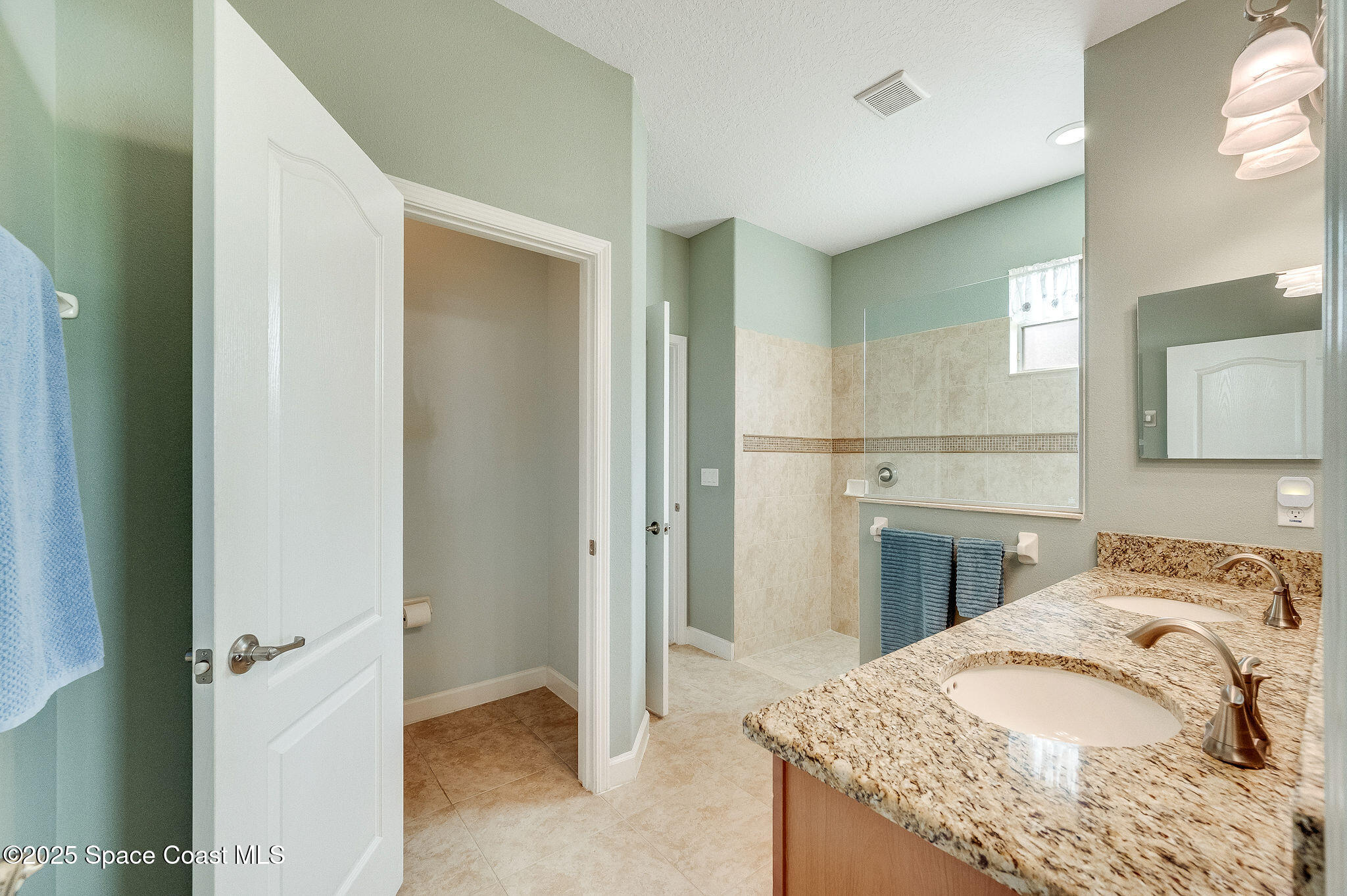 6531 Ingalls Street Melbourne, FL 32940 - Photo 12 of 46 a spacious bathroom with a granite countertop sink and a mirror