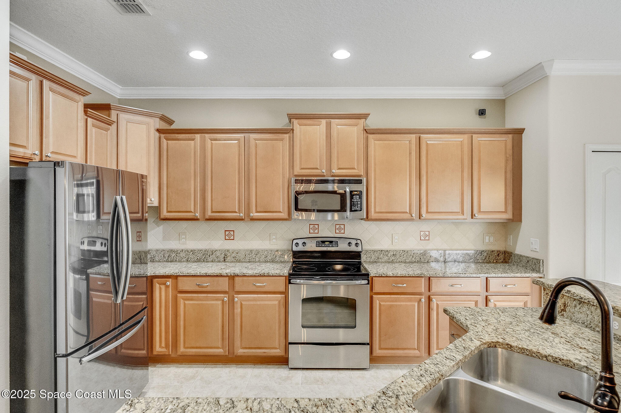 6531 Ingalls Street Melbourne, FL 32940 - Photo 38 of 46 a kitchen with stainless steel appliances granite countertop a stove a sink and a refrigerator