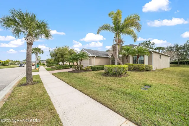 a front view of a house with a yard and palm trees