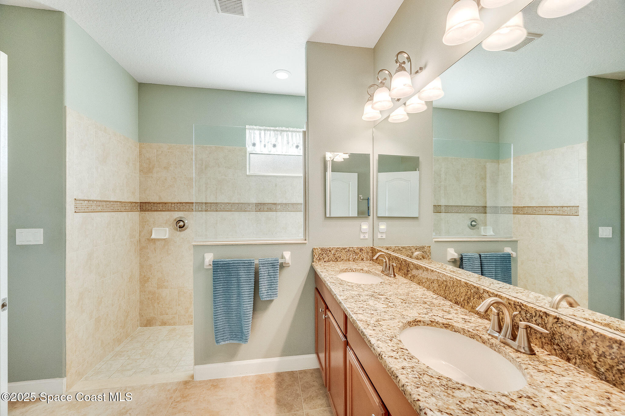 6531 Ingalls Street Melbourne, FL 32940 - Photo 44 of 46 a bathroom with a granite countertop double vanity sink a mirror and a shower
