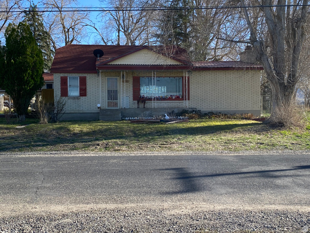 1766 Pine Rd Pine Canyon Tooele, UT 84074 - Photo 2 of 16 Light brick exterior featuring a red metal roof, covered front entry, and bay window