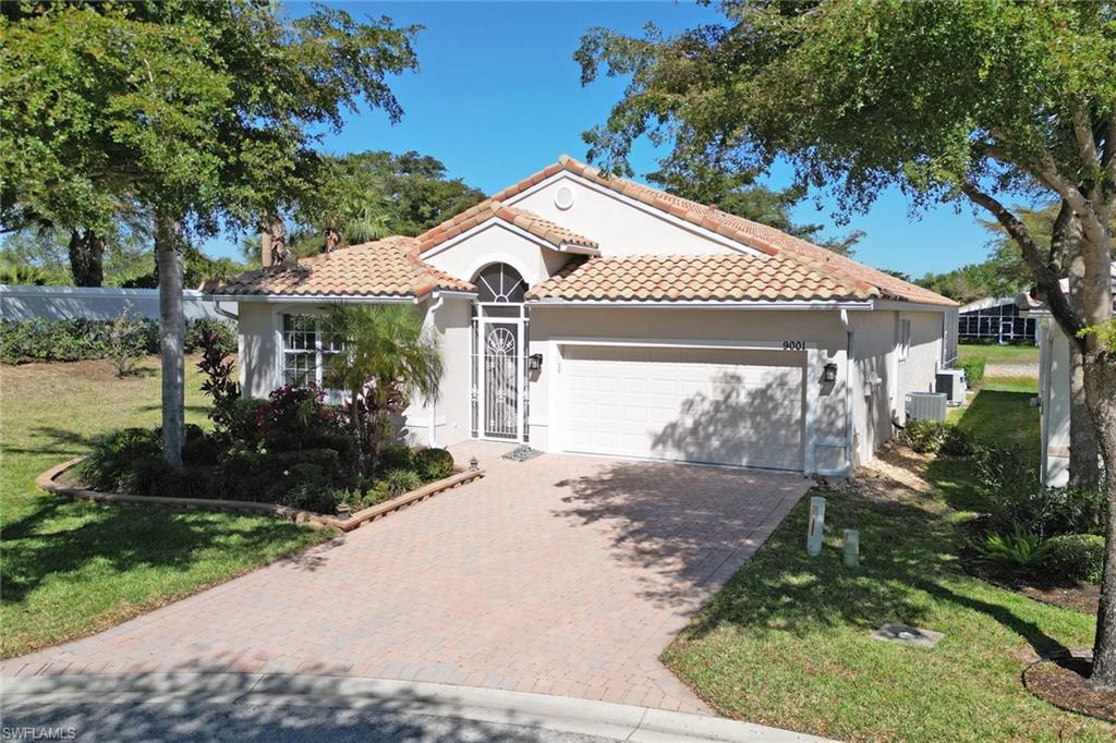 9001 Springview Loop Estero, FL 33928 - Photo 33 of 50 a view of a white house with a small yard plants and a large tree
