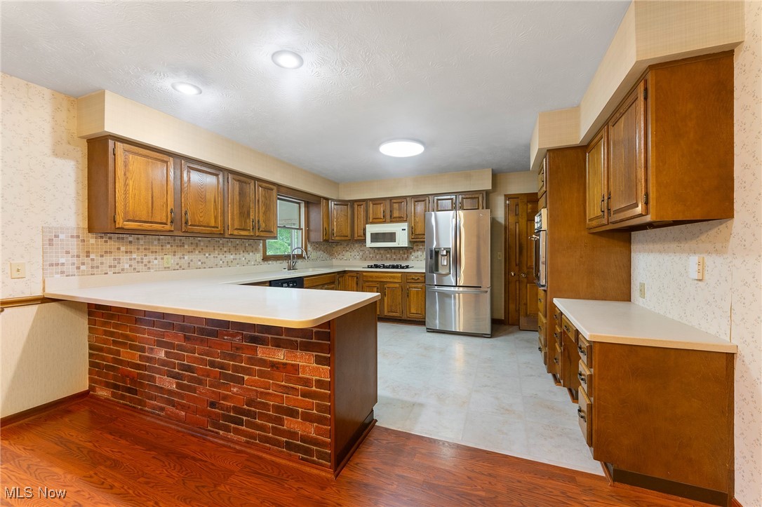 744 Johnson Plank Road Warren, OH 44481 - Photo 6 of 39 Kitchen featuring appliances, a peninsula, brown cabinets, light countertops.