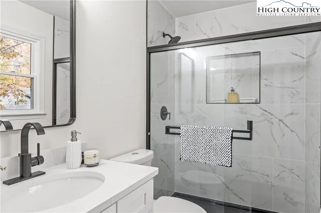 a view of a house with a small yard and wooden fence and large trees