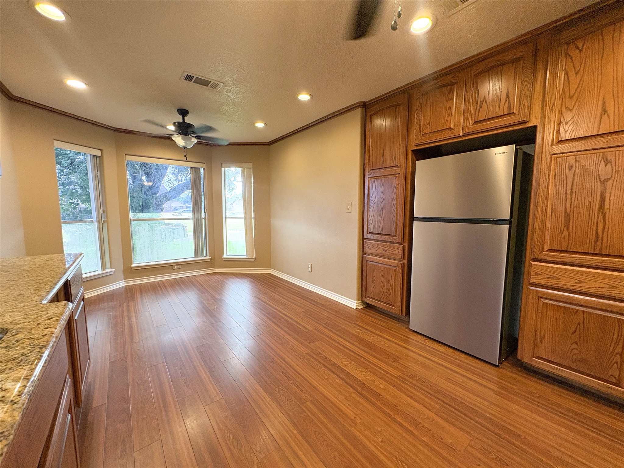 4503 Rattan Avenue Bay City, TX 77414 - Photo 4 of 14 Spacious kitchen with elegant hardwood floors, ample natural light from large bay windows, and abundant cabinetry surrounding a stainless steel refrigerator.