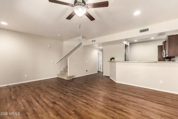 an empty room with wooden floor ceiling fan and windows