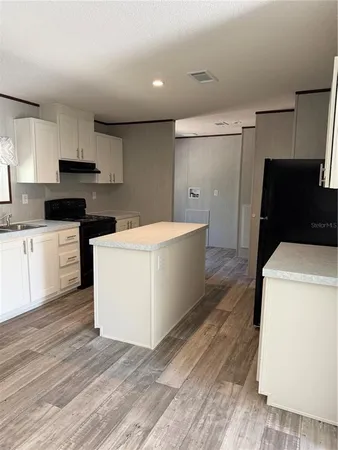 a kitchen with a refrigerator a stove top oven and white cabinets