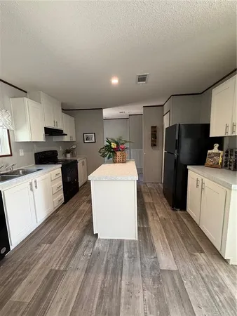 a kitchen with a sink wooden floor and stainless steel appliances