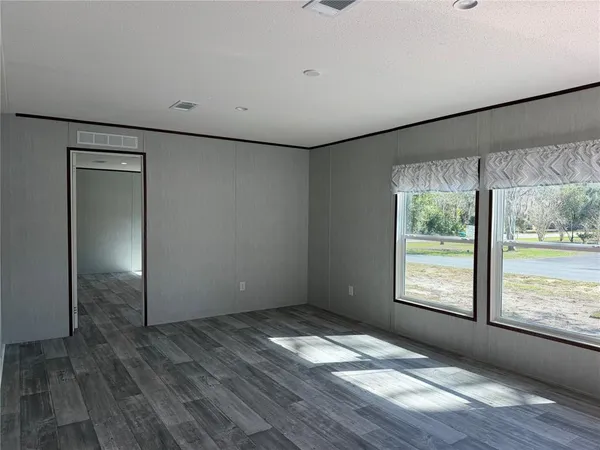 an empty room with wooden floor and windows