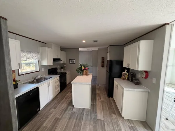 a kitchen with sink a microwave a refrigerator and wooden cabinets