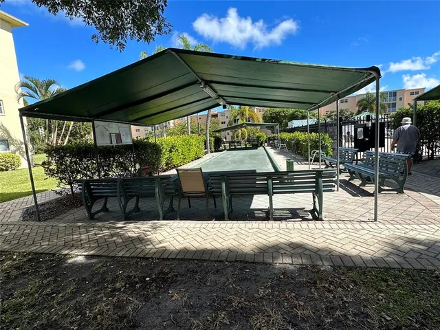 a view of patio with table and chairs under an umbrella with a small yard