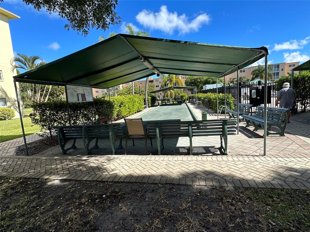 2300 Northeast 1st Lane, Unit 201 Boynton Beach, FL 33435 - Photo 25 of 34 a view of patio with table and chairs under an umbrella with a small yard