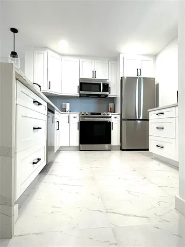 a kitchen with granite countertop a refrigerator and a stove top oven