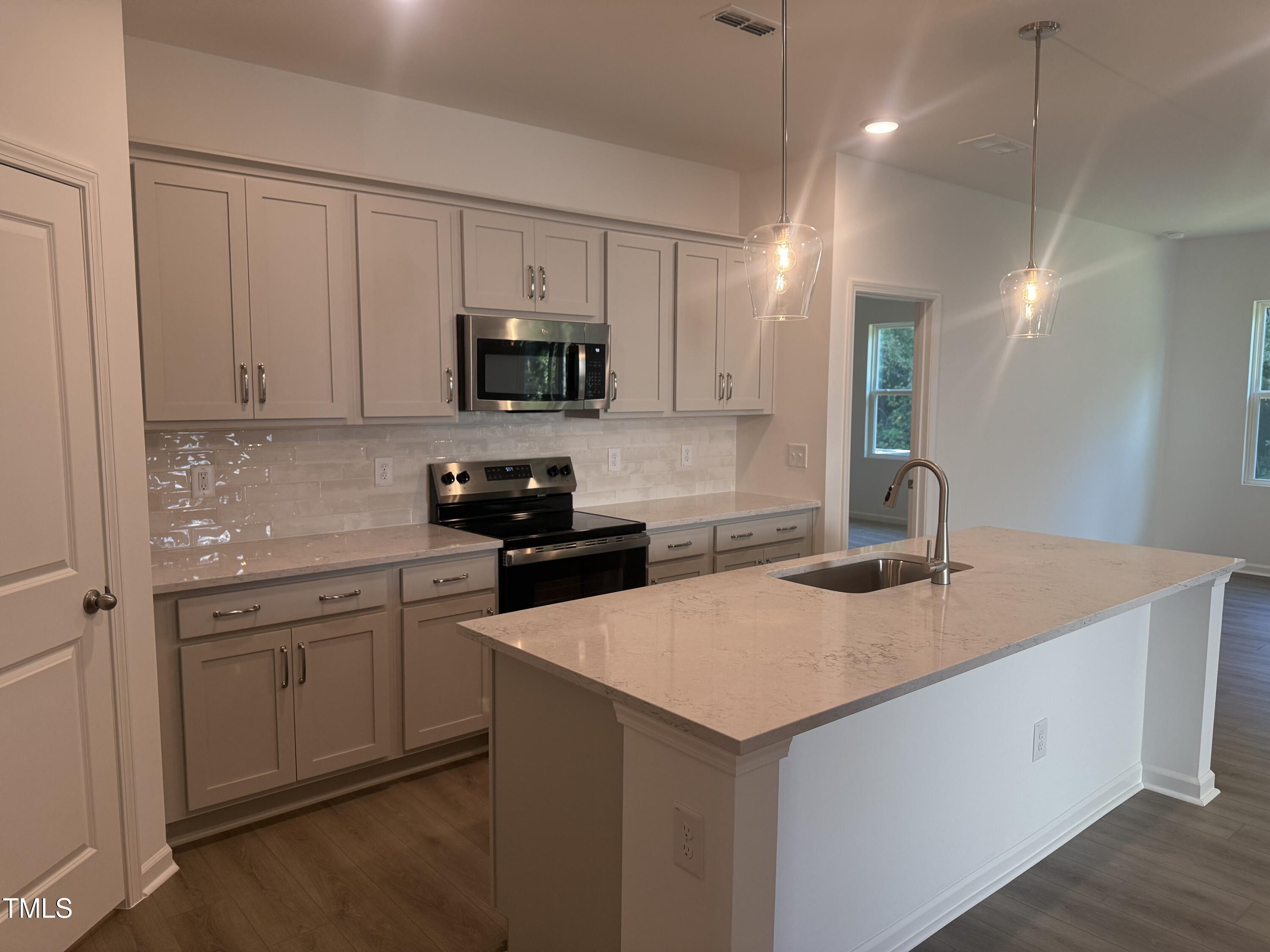 11185 Salers Loop Middlesex, NC 27557 - Photo 3 of 41 a kitchen with stainless steel appliances granite countertop a sink a stove a refrigerator a microwave oven with white cabinets