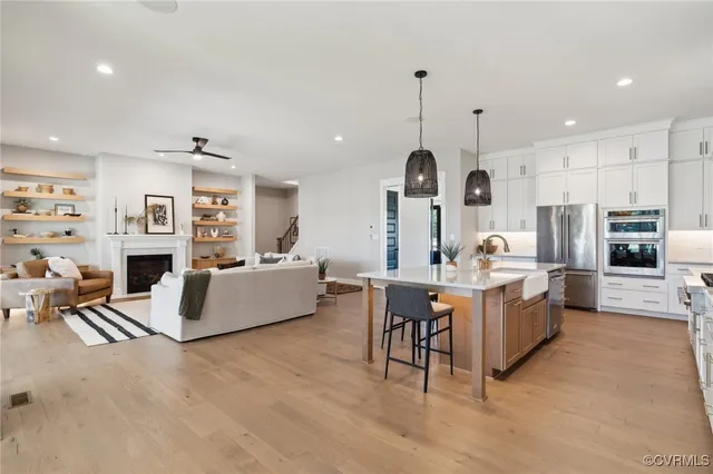 a large kitchen with kitchen island stainless steel appliances a table chairs sink and stove top oven