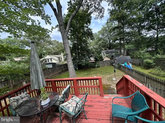 a balcony with wooden floor outdoor seating and yard in the back