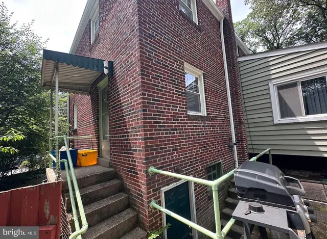 a backyard of a house with wooden chairs and potted plants