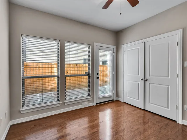 a view of empty room with wooden floor and fan