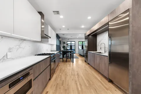 a kitchen with stainless steel appliances kitchen island hardwood floor sink stove refrigerator and cabinets