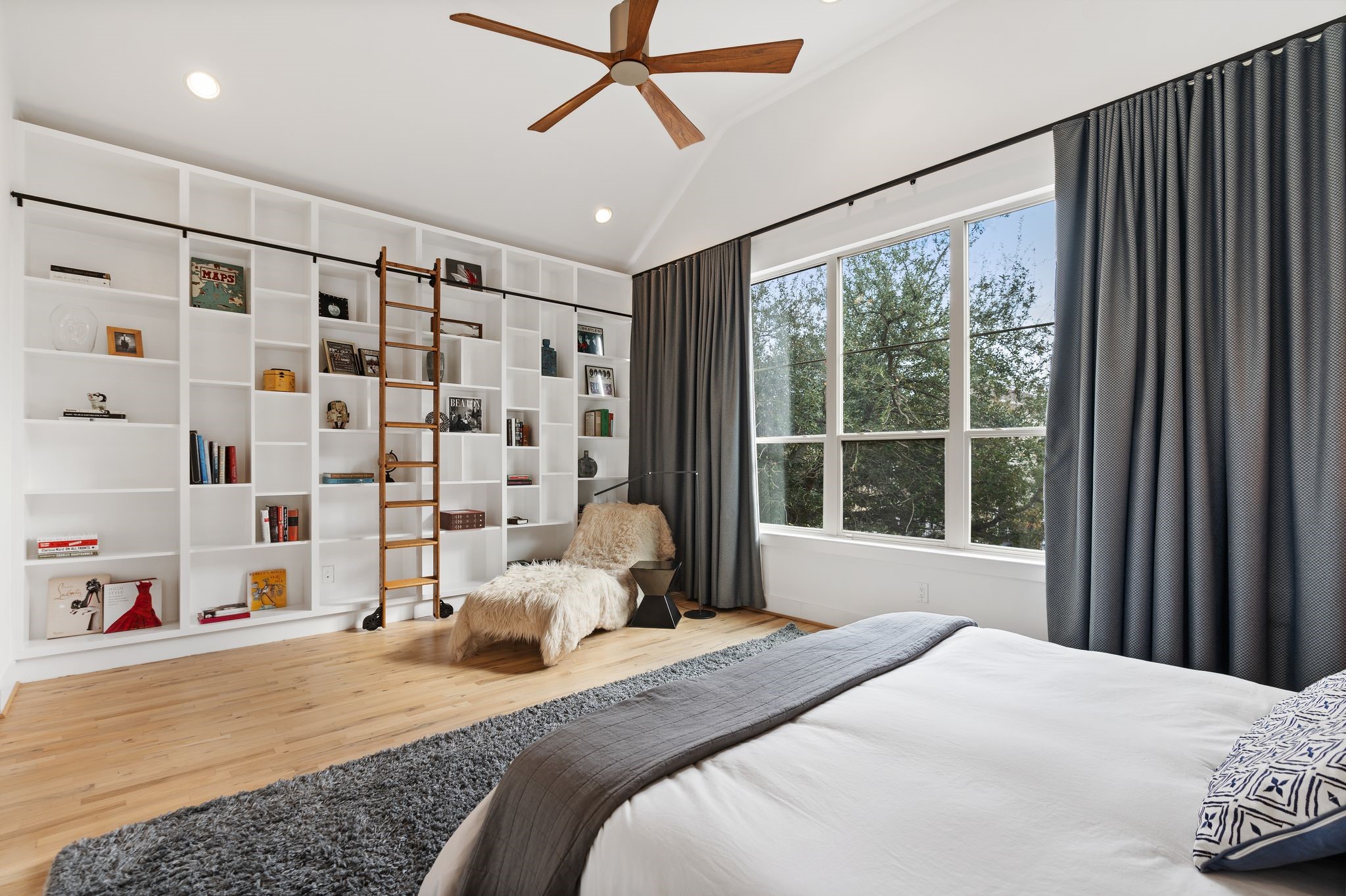 925 Waverly Street, Unit B Houston, TX 77008 - Photo 24 of 36 Sleep soundly in this tranquil primary bedroom featuring vaulted ceilings, a designer wood ceiling fan, and custom-built shelving with a library ladder.