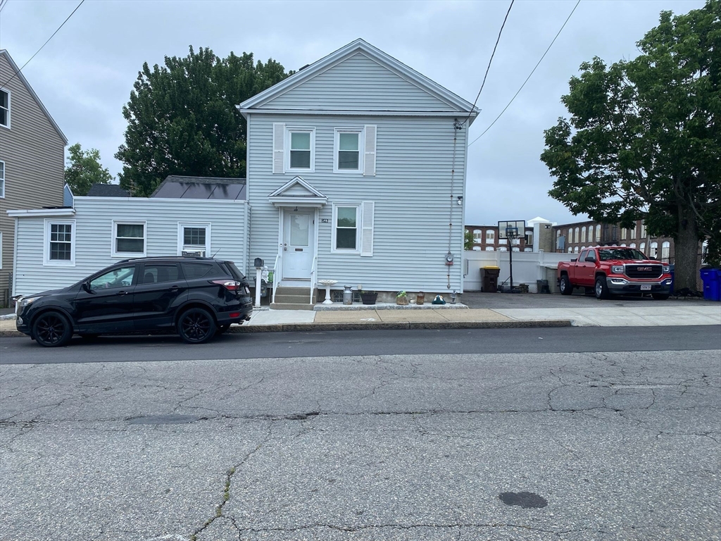 a black and white car parked in front of white house