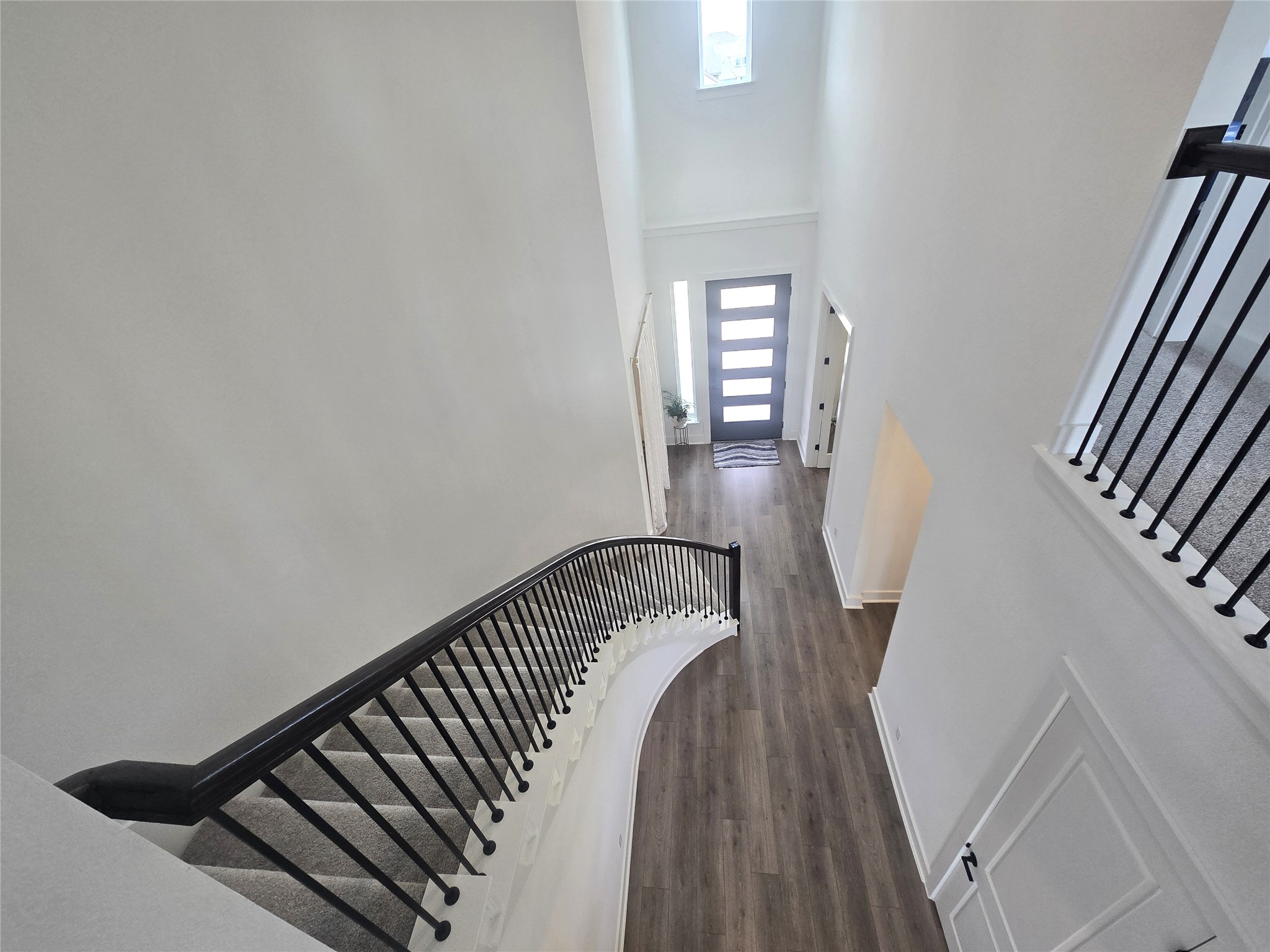 124 Ribera Drive Liberty Hill, TX 78642 - Photo 15 of 40 Elegant staircase with sleek black railings descends to a bright foyer featuring wood-look flooring.