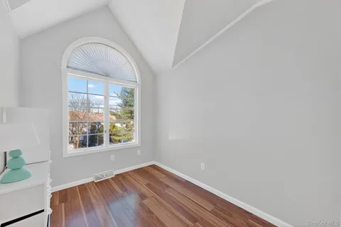 a view of a hallway with wooden floor and a bathroom