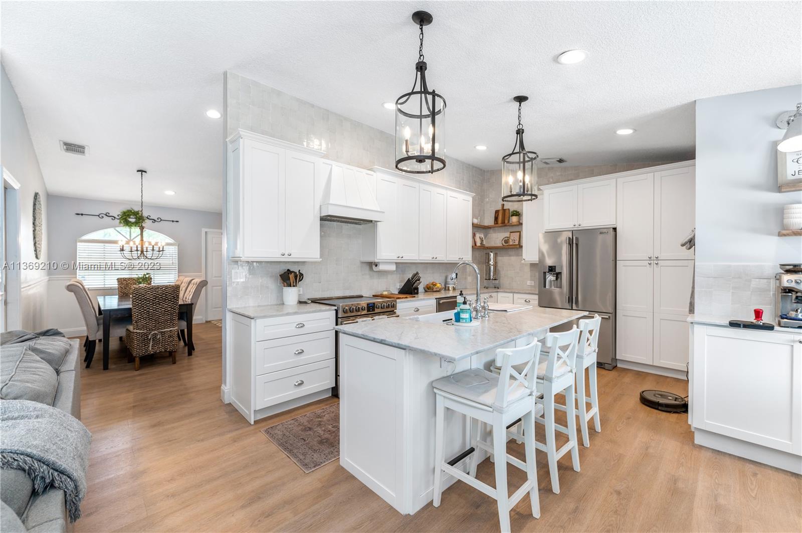 18217 Southwest 148th Ave Road Miami, FL 33187 - Photo 9 of 29 a kitchen with white cabinets stainless steel appliances and dining table
