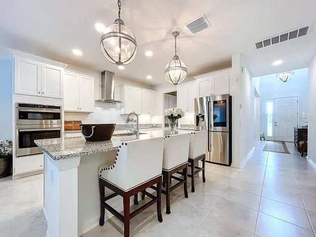 a kitchen with stainless steel appliances granite countertop a refrigerator a stove a sink dishwasher a dining table and chairs with wooden floor