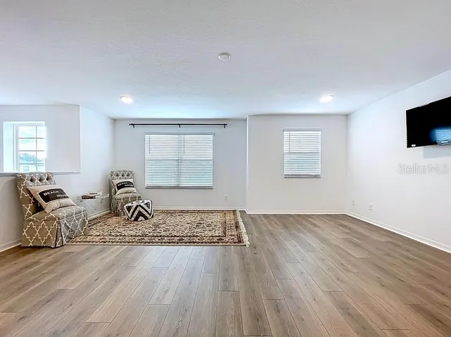 a living room with furniture a flat screen tv and a window