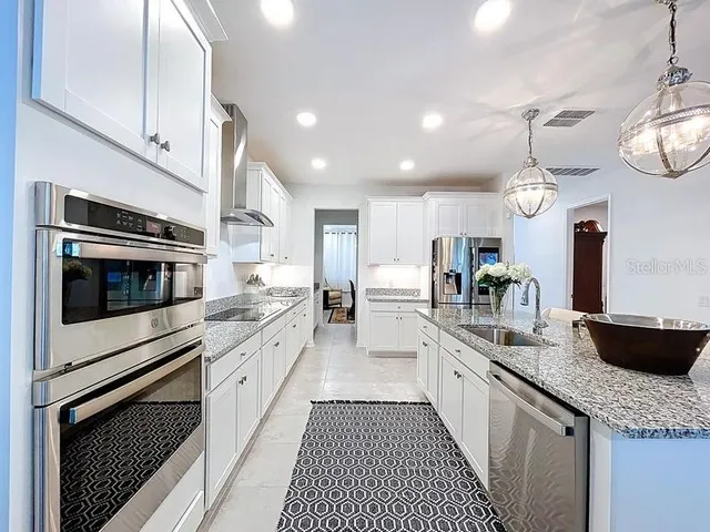 a large kitchen with granite countertop a stove top oven a sink dishwasher a dining table and chairs with wooden floor