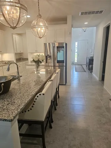 a kitchen with granite countertop a stove a sink a dining table and chairs