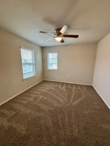 en empty room with windows and ceiling fan