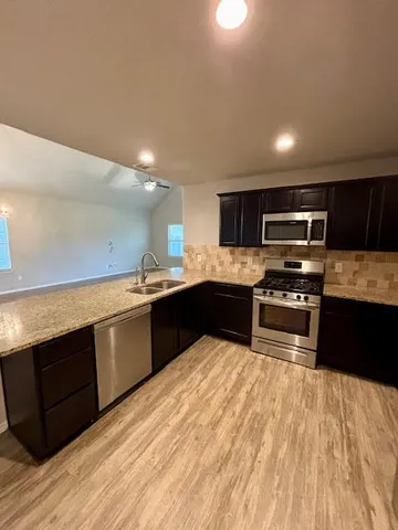 a kitchen with stainless steel appliances kitchen island granite countertop a sink and a stove