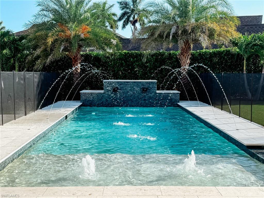 1702 Ludlow Road Marco Island, FL 34145 - Photo 42 of 47 Rectangular swimming pool featuring a tiered stone-finish water feature, multiple water jets, and a baja shelf