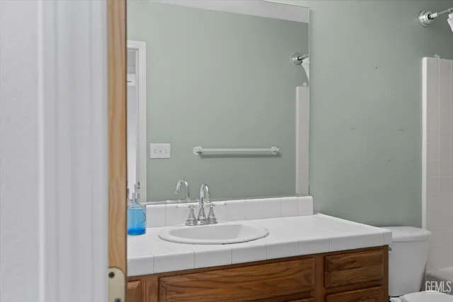 a bathroom with a granite countertop sink a toilet and shower