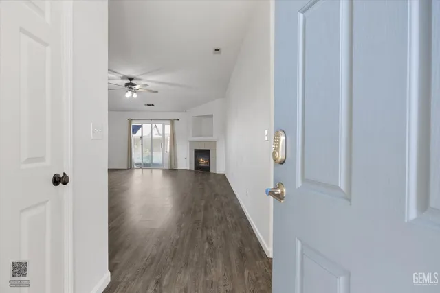 a view of an empty room with wooden floor and a fireplace