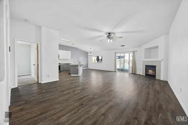 a view of an empty room with wooden floor fireplace and a window