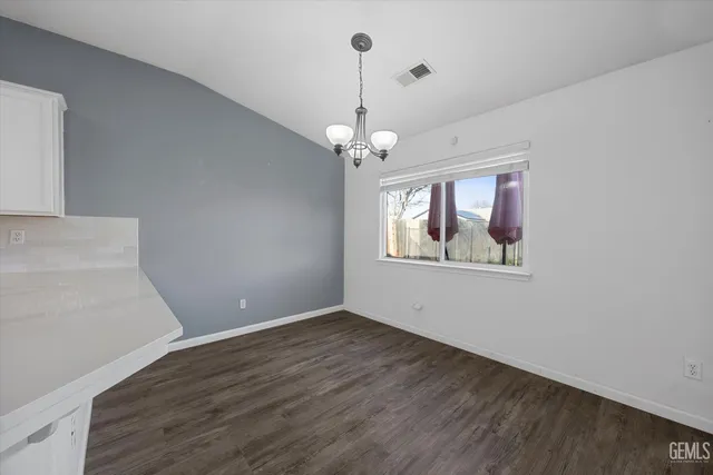 a kitchen with granite countertop a stove a sink and white cabinets with wooden floor