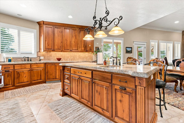 11290 South Southfield Road Mayfield, UT 84643 - Photo 54 of 103 Kitchen featuring extensive wood cabinetry, a central island with a built-in sink, stone countertops, and tile flooring