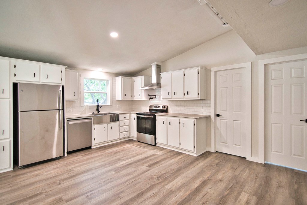425 Post Hill Street Mason, TX 76856 - Photo 5 of 21 a kitchen with a refrigerator wooden floor and white cabinets