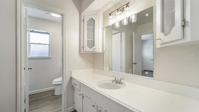a bathroom with a granite countertop sink mirror and a toilet