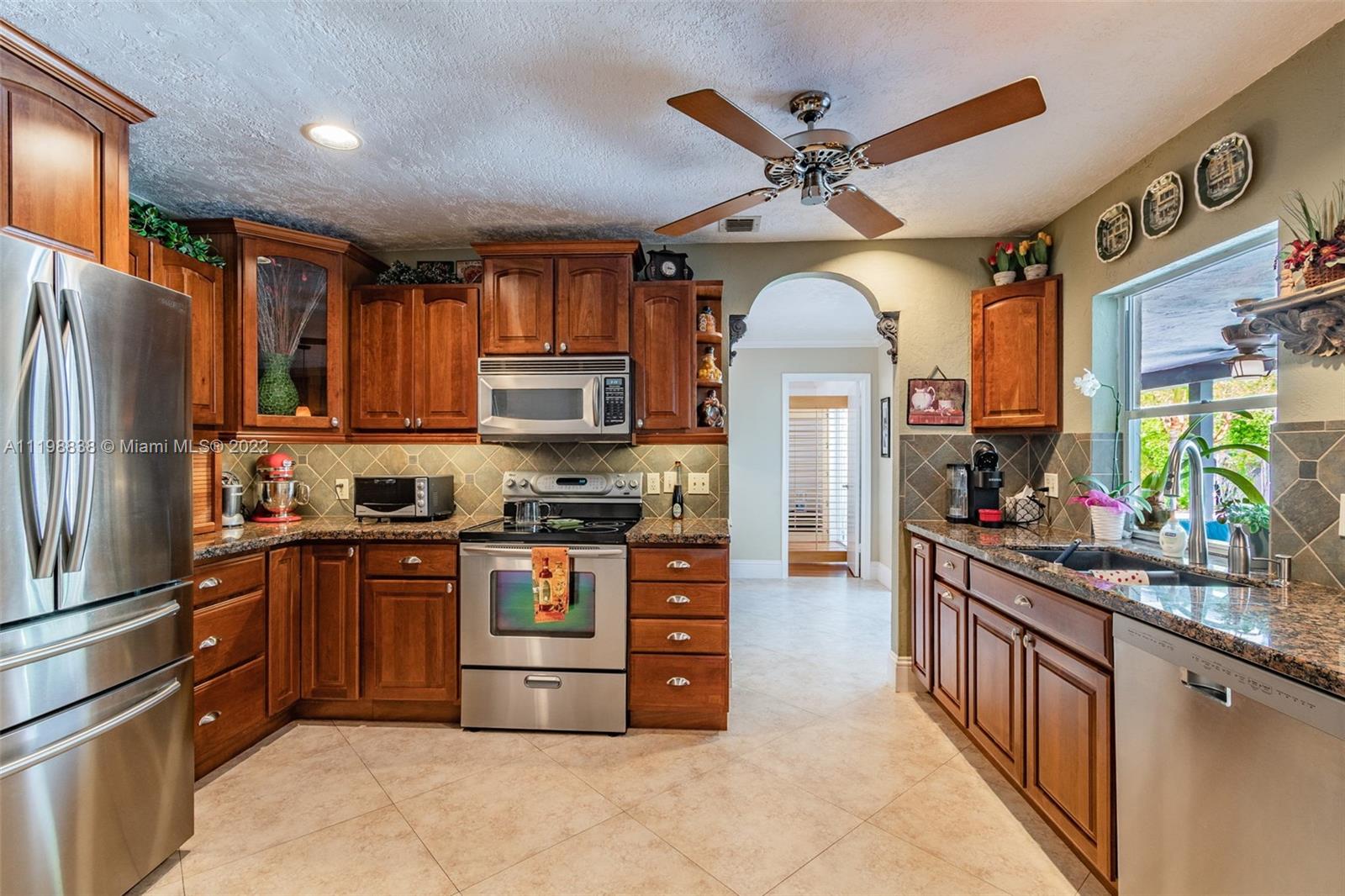 3015 Dunlin Road Delray Beach, FL 33444 - Photo 16 of 47 a kitchen with stainless steel appliances granite countertop a refrigerator a stove a sink and a microwave