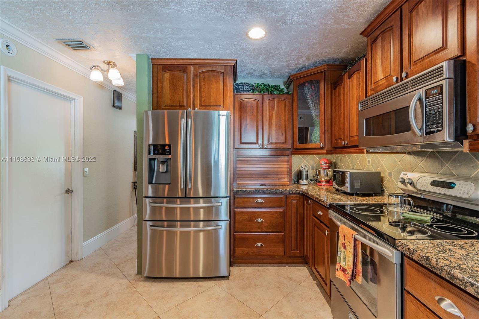 3015 Dunlin Road Delray Beach, FL 33444 - Photo 18 of 47 a kitchen with stainless steel appliances granite countertop a stove top oven a refrigerator and a sink