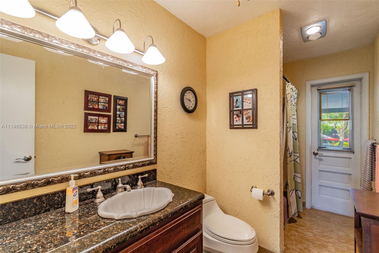 3015 Dunlin Road Delray Beach, FL 33444 - Photo 29 of 47 a bathroom with a granite countertop toilet sink and mirror