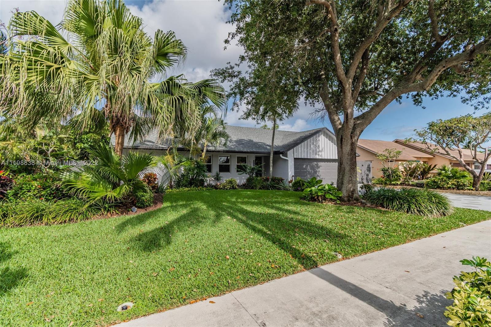 3015 Dunlin Road Delray Beach, FL 33444 - Photo 4 of 47 a front view of a house with a yard and potted plants