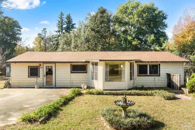 a front view of house with yard and trees in the background
