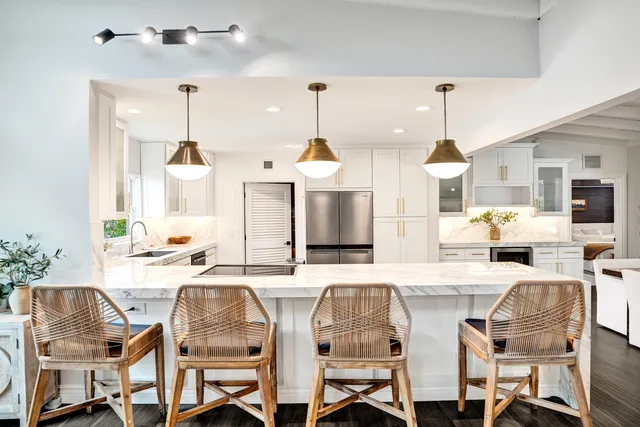 a kitchen with stainless steel appliances kitchen island granite countertop a dining table chairs and white cabinets